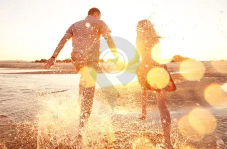 Galapagos-honeymoon-Couple-running-through-the-ocean-holding-hands-during-sunset