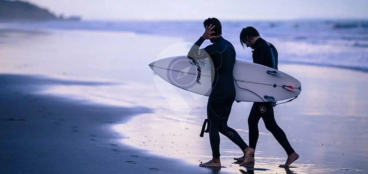 Galapagos wetsuits - surfers walking on beach