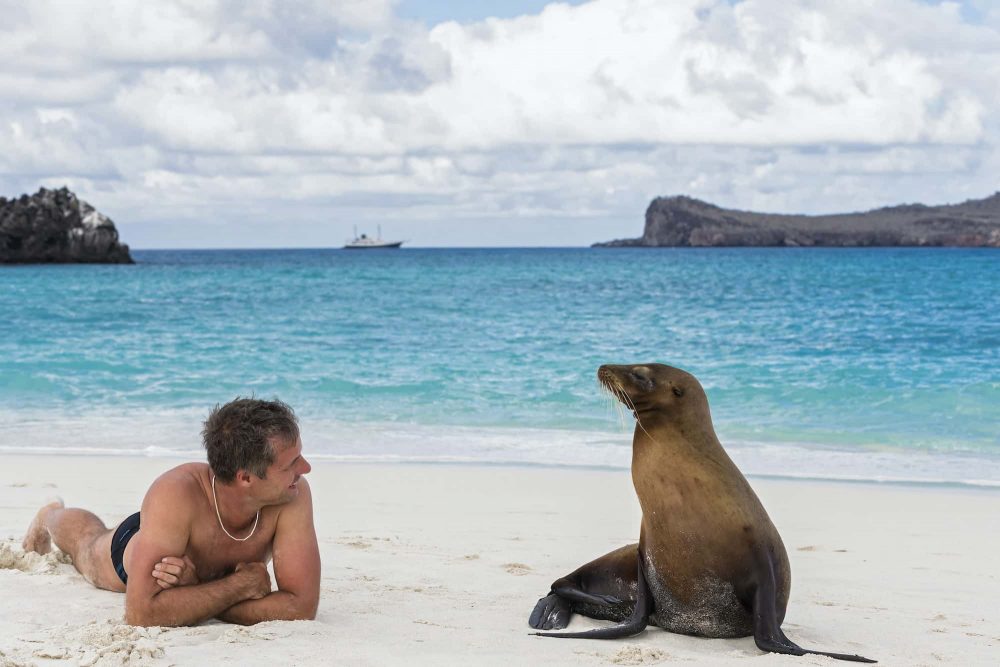 Ecuador, Galapagos Islands, Espanola, tourist and Galapagos sea lion on beach