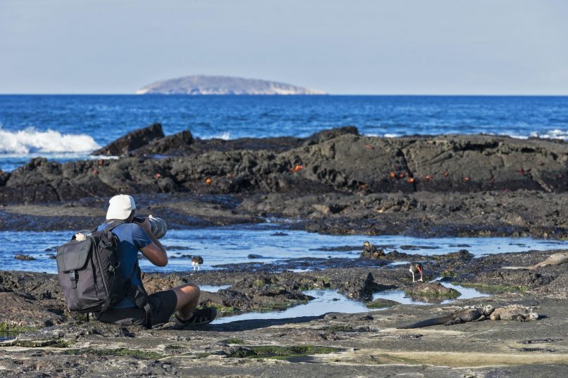 Best time to visit Galapagos - Ecuador, Galapagos Islands, Santiago, man photographing at seafront